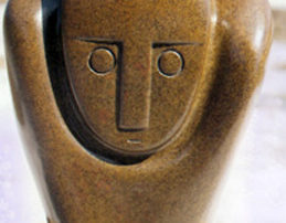 Shona stone sculpture with a smooth rounded form and a stylized human face carved into warm brown stone. Featured on a page about Shona sculpture and African art.